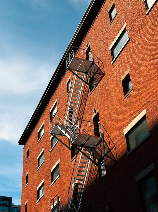 Red brick building with fire escapes under a blue sky